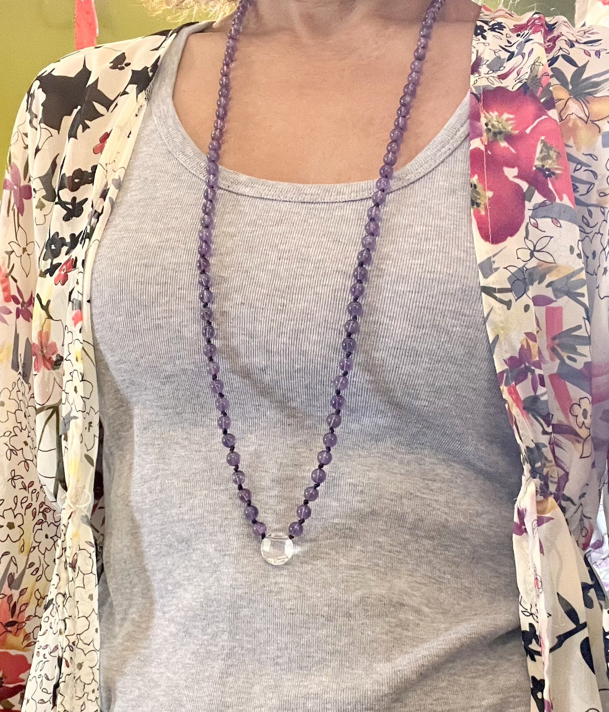 Sautoir mala améthyste 108 perles porté sur un t-shirt gris, pendentif cristal de roche, longueur 86 cm
