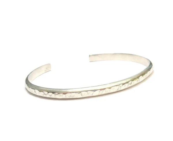 Bracelet jonc ouvert en argent massif martelé, avec un design épuré. Taille unique et réglable, s'adaptant facilement au poignet pour un confort optimal. Un bijou intemporel et élégant. Diamètre intérieur de 60 mm, épaisseur de 5 x 2,5 mm.