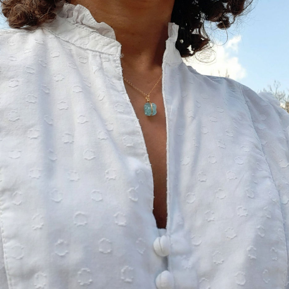 Femme portant un collier en argent doré avec aigue-marine brute, éclairage doux naturel 