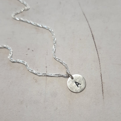 Gros plan sur la gravure de l'initiale du collier en argent massif