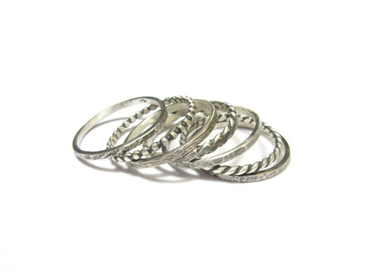Ensemble de 7 bagues fines pour femme en argent massif patiné. Design semainier symbolique : Composée de 7 anneaux fins, cette bague représente les 7 jours de la semaine – un rappel discret du cycle de la vie et du temps.