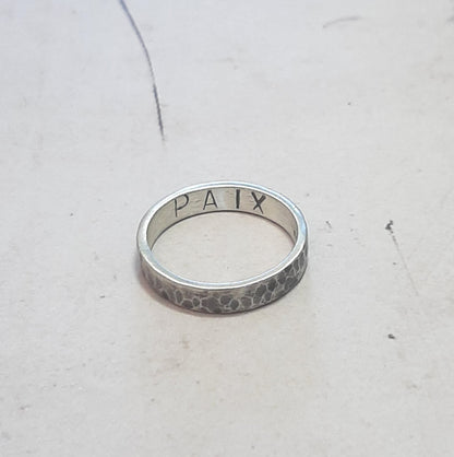 Bague en argent massif martelé et patiné, au design unique et artisanal. L'intérieur de l'anneau présente une gravure personnalisable, jusqu'à 6 caractères, offrant la possibilité d'y inscrire un message, une date ou un prénom. 
Bijoux écoresponsables en argent.