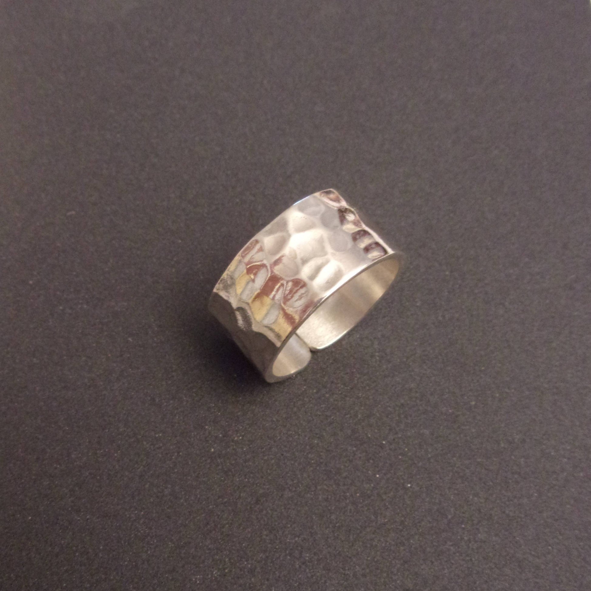 Bague large en argent massif martelé, au design à la fois moderne et intemporel. Avec une largeur de 10 mm, l'anneau se distingue par son allure contemporaine et sa solidité, offrant une pièce durable et résistante à l'usure. Ce bijou élégant s'adapte à tous les styles et ne se démode jamais, en faisant un choix parfait pour toute occasion.