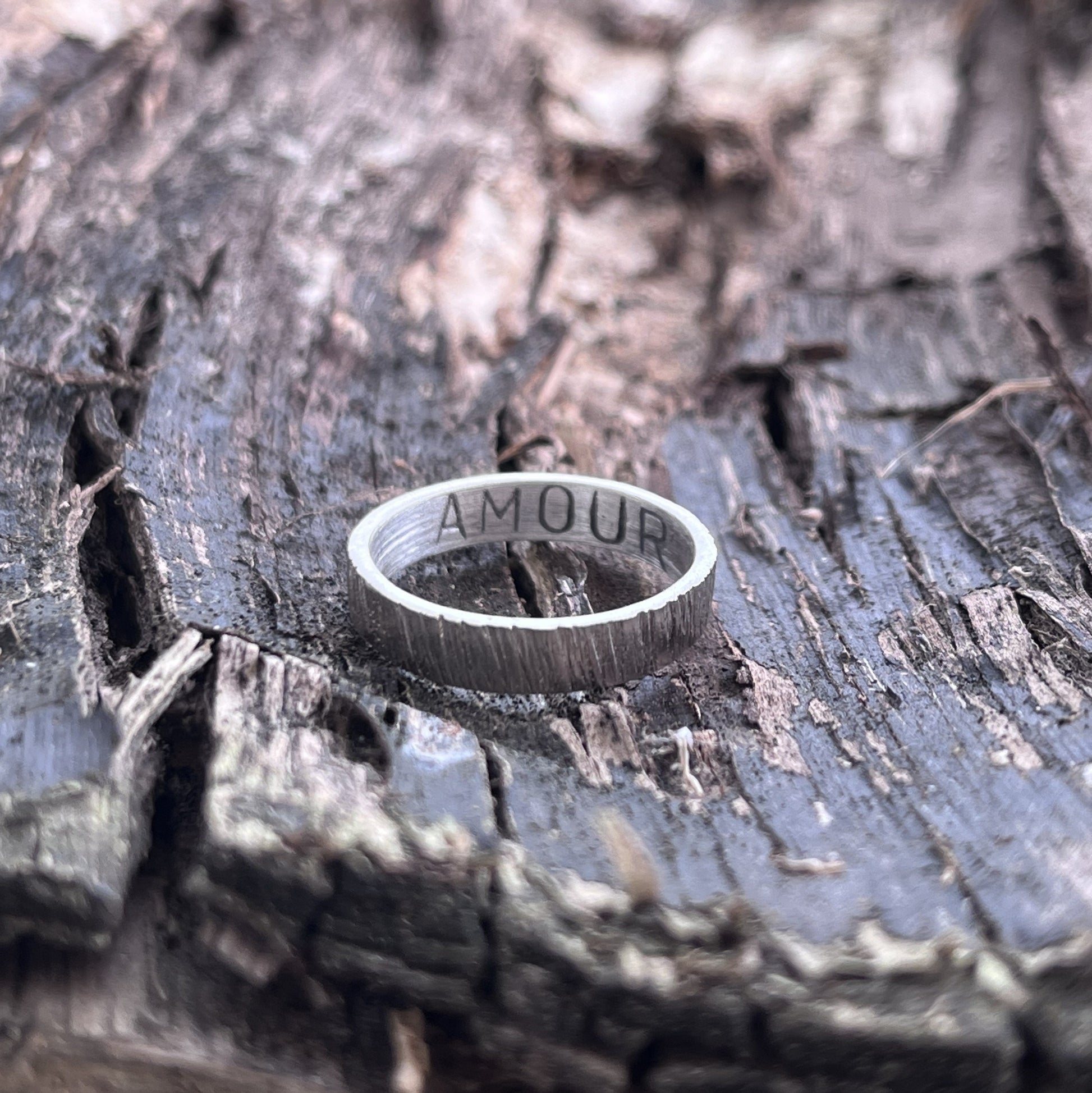 Bague en argent massif martelé et patiné, au design unique et artisanal. L'intérieur de l'anneau présente une gravure personnalisable, jusqu'à 6 caractères, offrant la possibilité d'y inscrire un message, une date ou un prénom. Avec une largeur d'environ 4 mm, cette bague allie élégance et sobriété. Les demandes spécifiques pour une création sur mesure sont les bienvenues.