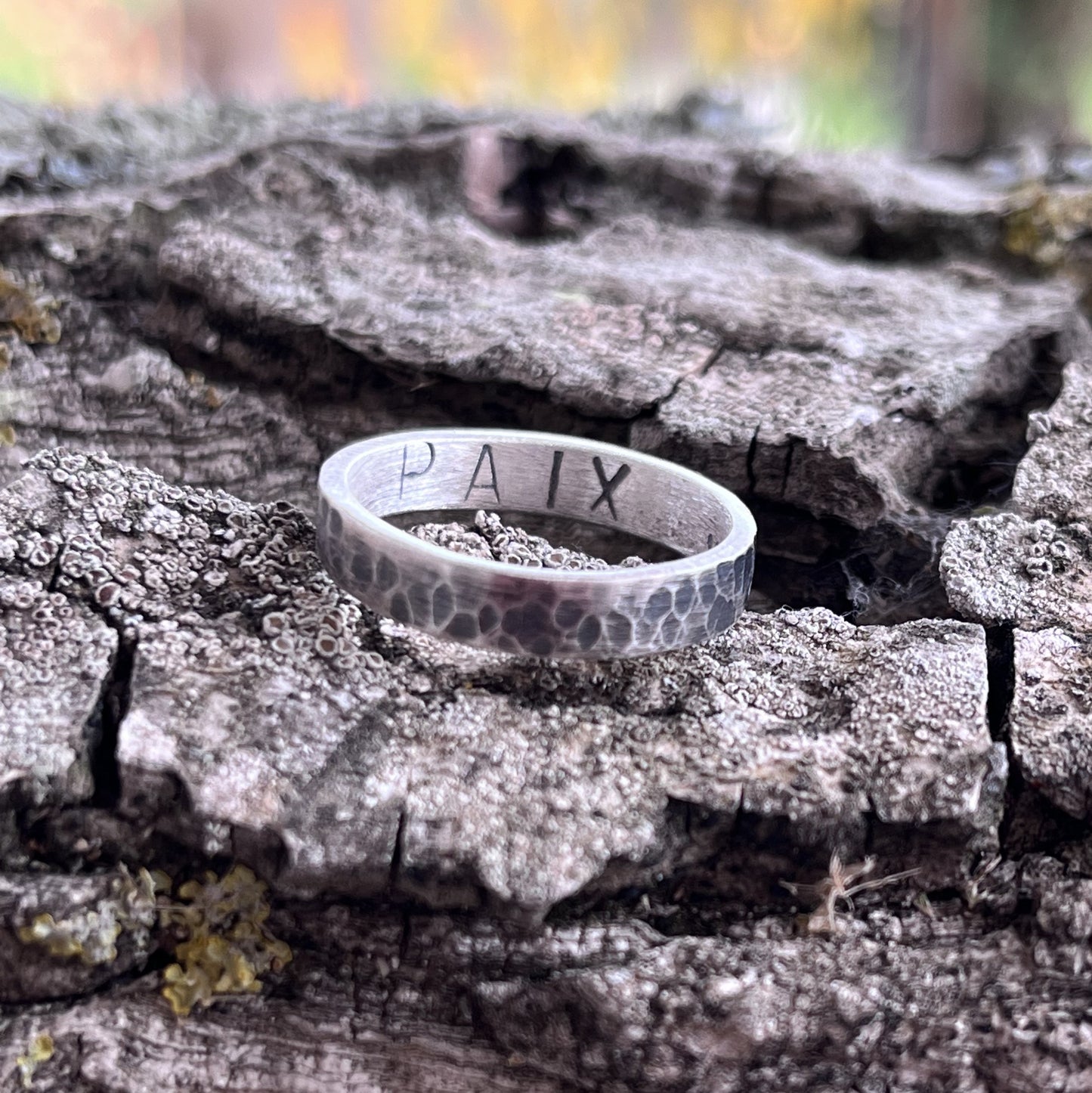 Bague en argent massif martelé et patiné, au design unique et artisanal. L'intérieur de l'anneau présente une gravure personnalisable, jusqu'à 6 caractères, offrant la possibilité d'y inscrire un message, une date ou un prénom. Avec une largeur d'environ 4 mm, cette bague allie élégance et sobriété. Les demandes spécifiques pour une création sur mesure sont les bienvenues. Bijoux non genrés.
Bague à personnaliser.