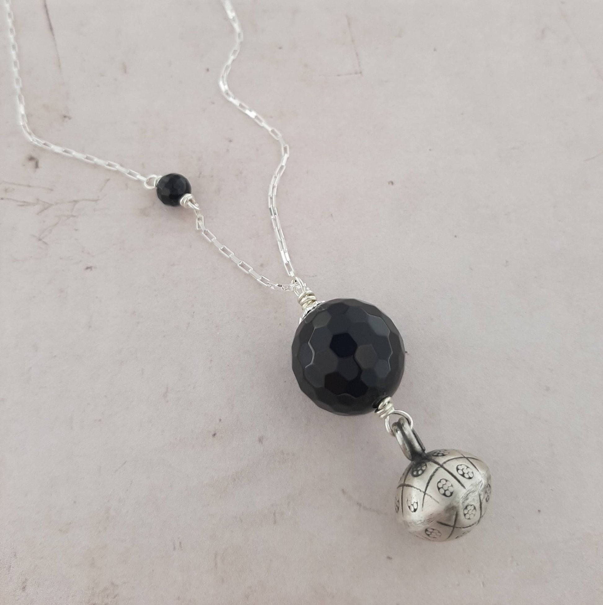 Bijoux de grossesse, Sautoir Bola Argent 925 et Pierres Naturelles Sautoir bola en argent 925 avec pierres naturelles. Ce bijou emblématique est porté par les femmes indonésiennes tout au long de leur grossesse. Le pendentif bola, en argent véritable, repose délicatement sur leur ventre et émet un son doux et apaisant à chaque mouvement, offrant confort et sérénité au bébé. bijoux de grossesse, sautoir bola argent 925, pendentif en argent, pierres naturelles, onyx facetté, tradition indonésienne, bébé. 