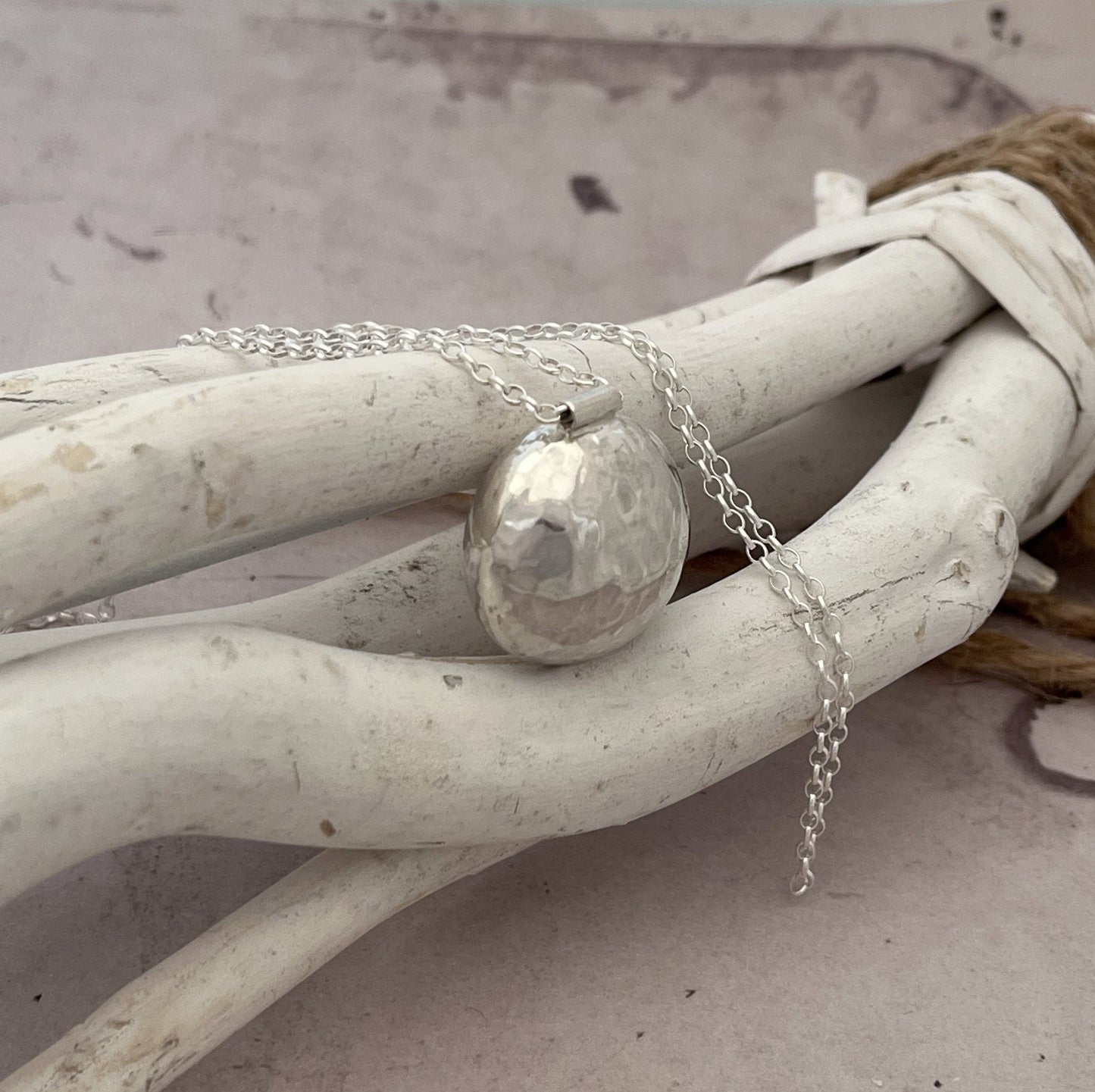 Le sautoir bola en argent massif martelé est un magnifique bijou de grossesse imprégné de tradition. Inspiré des coutumes indonésiennes, ce pendentif bola repose délicatement sur le ventre des femmes enceintes, émettant un tintement doux et apaisant à chaque mouvement. Le son harmonieux qu'il produit est censé calmer le bébé in utero, créant ainsi un lien particulier entre la mère et l'enfant à naître.

