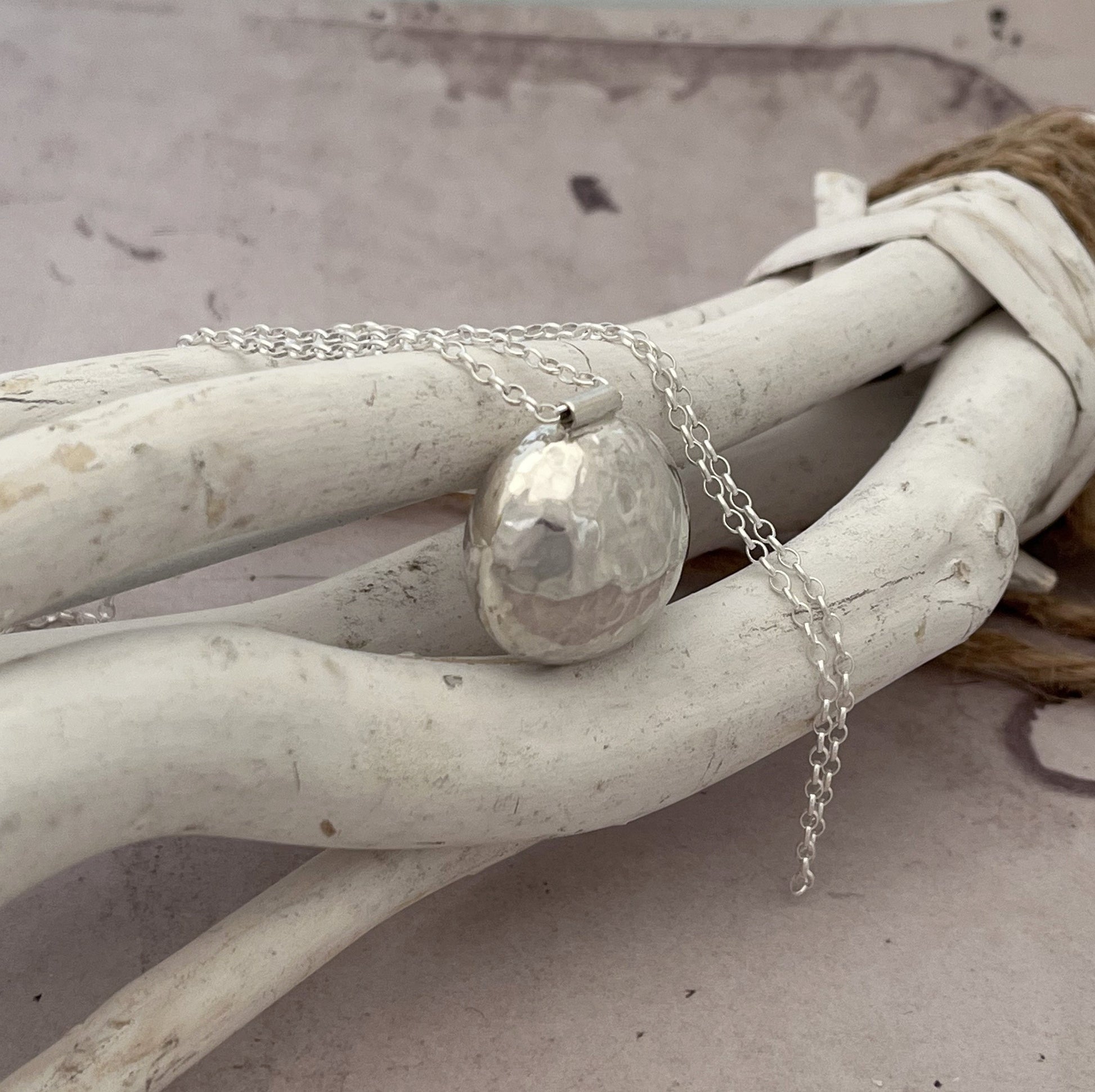Le sautoir bola en argent massif martelé est un magnifique bijou de grossesse imprégné de tradition. Inspiré des coutumes indonésiennes, ce pendentif bola repose délicatement sur le ventre des femmes enceintes, émettant un tintement doux et apaisant à chaque mouvement. Le son harmonieux qu'il produit est censé calmer le bébé in utero, créant ainsi un lien particulier entre la mère et l'enfant à naître.

