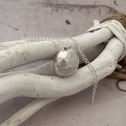 Le sautoir bola en argent massif martelé est un magnifique bijou de grossesse imprégné de tradition. Inspiré des coutumes indonésiennes, ce pendentif bola repose délicatement sur le ventre des femmes enceintes, émettant un tintement doux et apaisant à chaque mouvement. Le son harmonieux qu'il produit est censé calmer le bébé in utero, créant ainsi un lien particulier entre la mère et l'enfant à naître.

