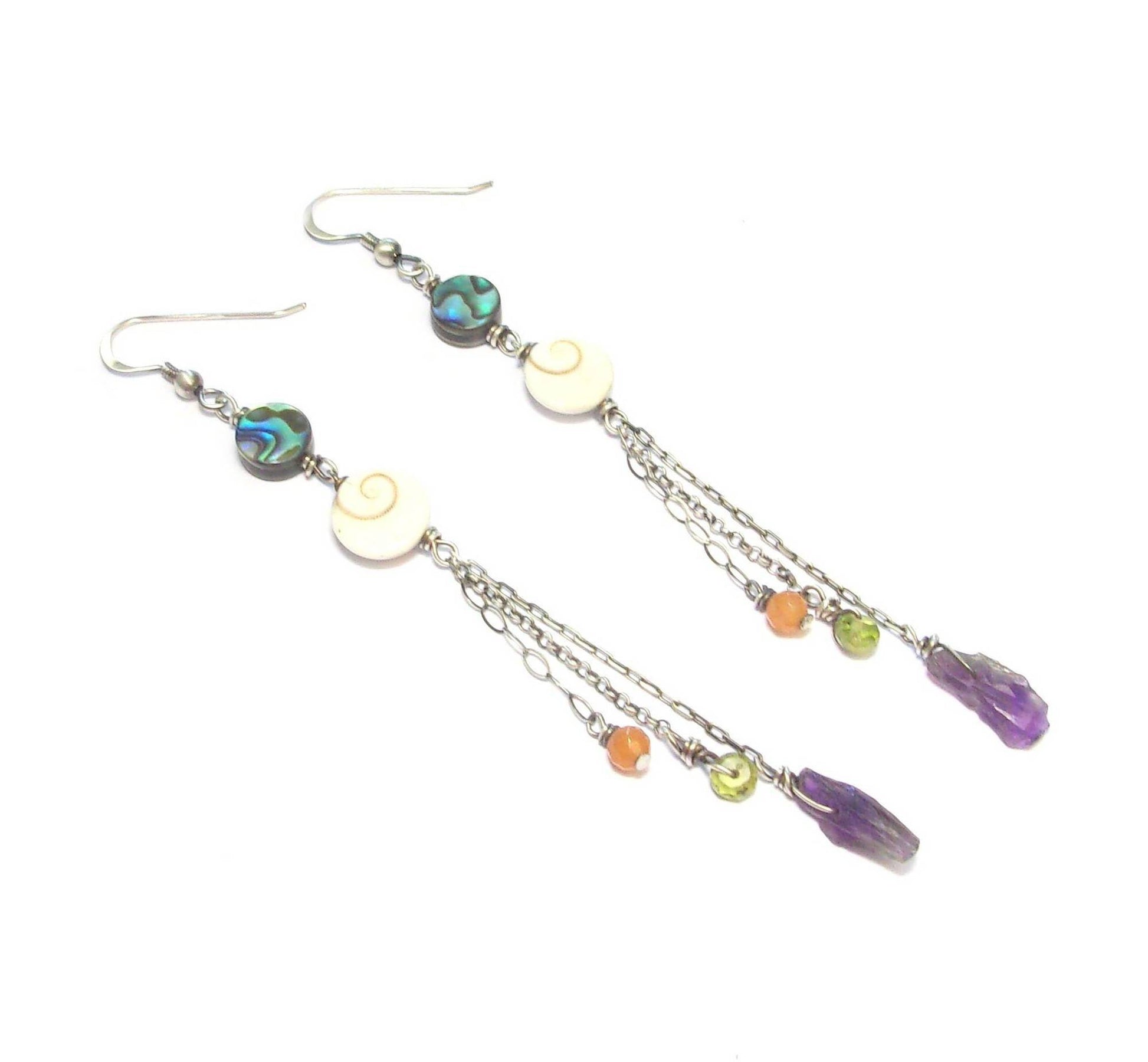 Boucles d'oreilles ethniques longues en argent patiné noir, ornées de coquillages et de pierres naturelles telles que l'améthyste, le péridot et l'aventurine. Les pierres et coquillages, étant naturels, présentent des variations de forme et de couleur. La longueur est de 10 cm.