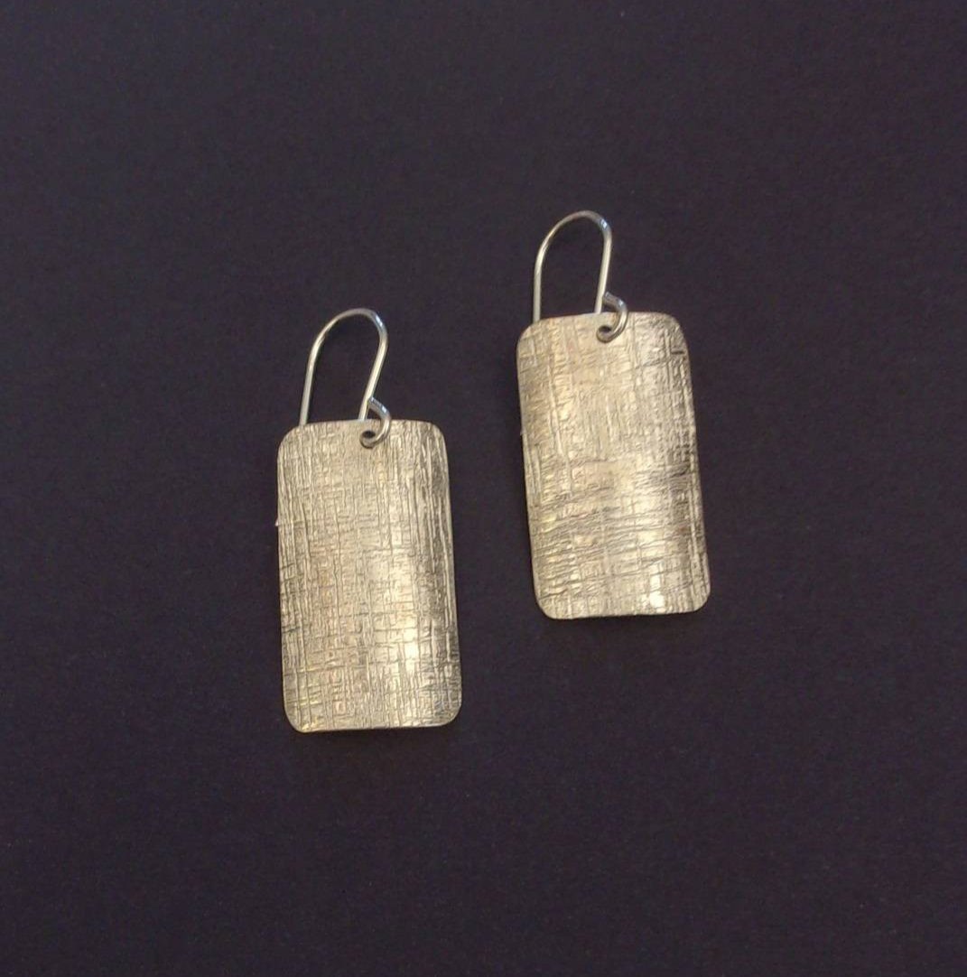 Ces boucles d'oreilles en argent massif ciselé, de forme rectangulaire, conviennent parfaitement à toutes les occasions. Leur design intemporel ajoute une touche d'élégance et de sophistication à toutes vos tenues.