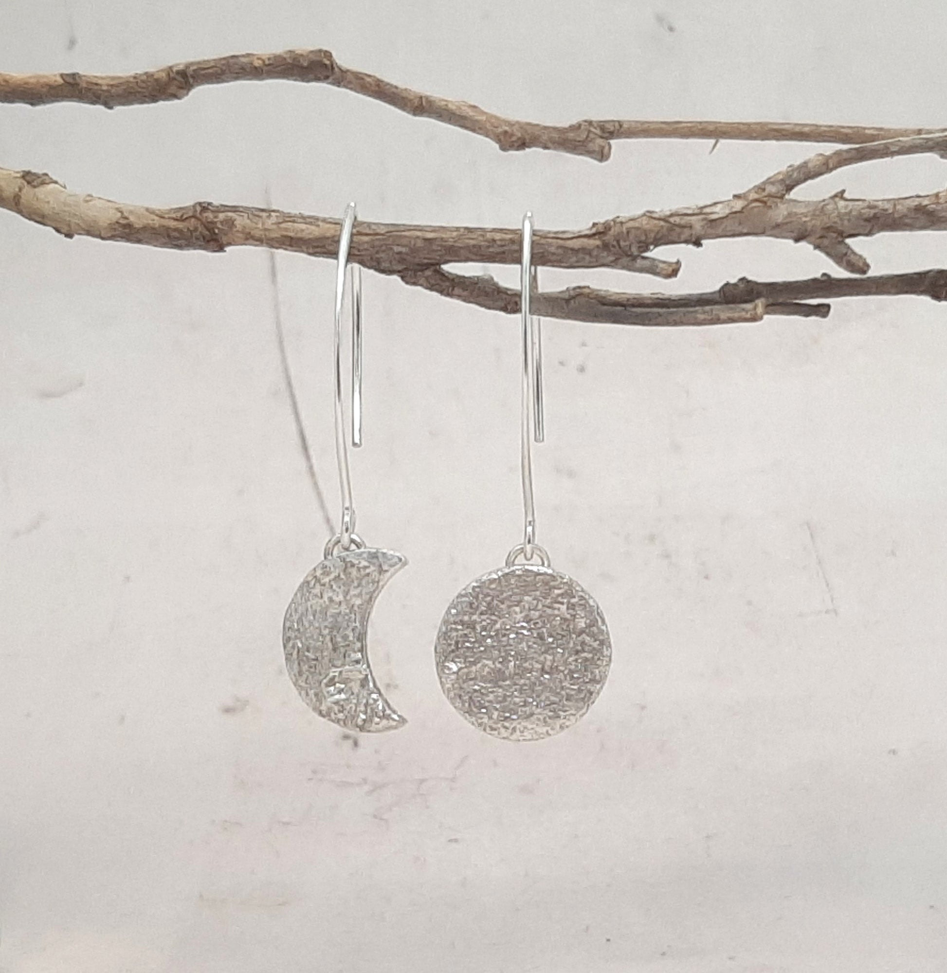 Ces boucles d'oreilles asymétriques en argent massif, inspirées de la mythologie tupi-guarani, représentent un croissant et une pleine lune. Chaque pièce est faite main, avec une texture organique unique. Le design élégant et raffiné rappelle la beauté mystique de Jaci, déesse de la lune.