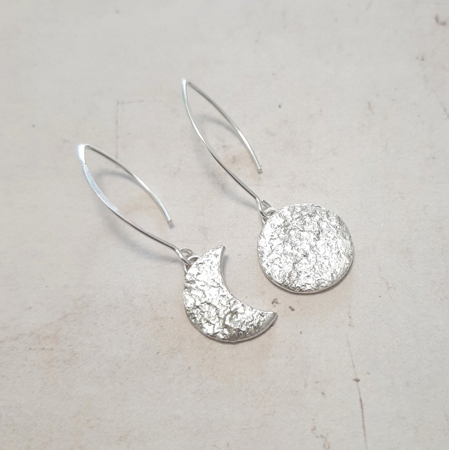 Ces boucles d'oreilles asymétriques en argent massif réticulé, représentant un croissant de lune et une pleine lune, présentent une texture organique unique.