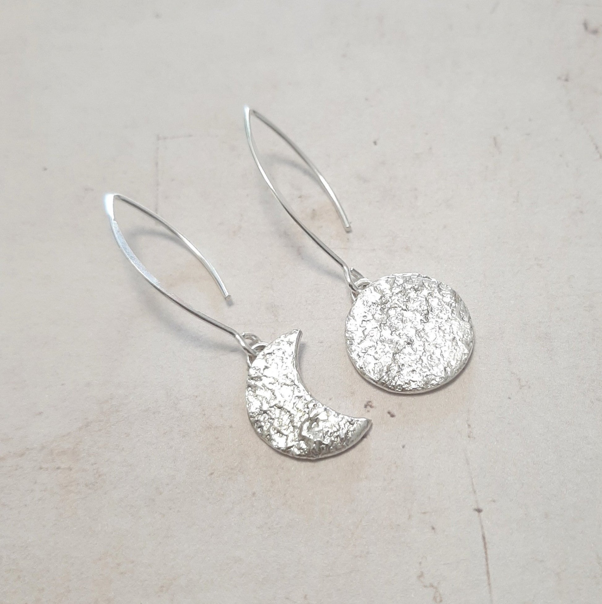 Ces boucles d'oreilles asymétriques en argent massif réticulé, représentant un croissant de lune et une pleine lune, présentent une texture organique unique.