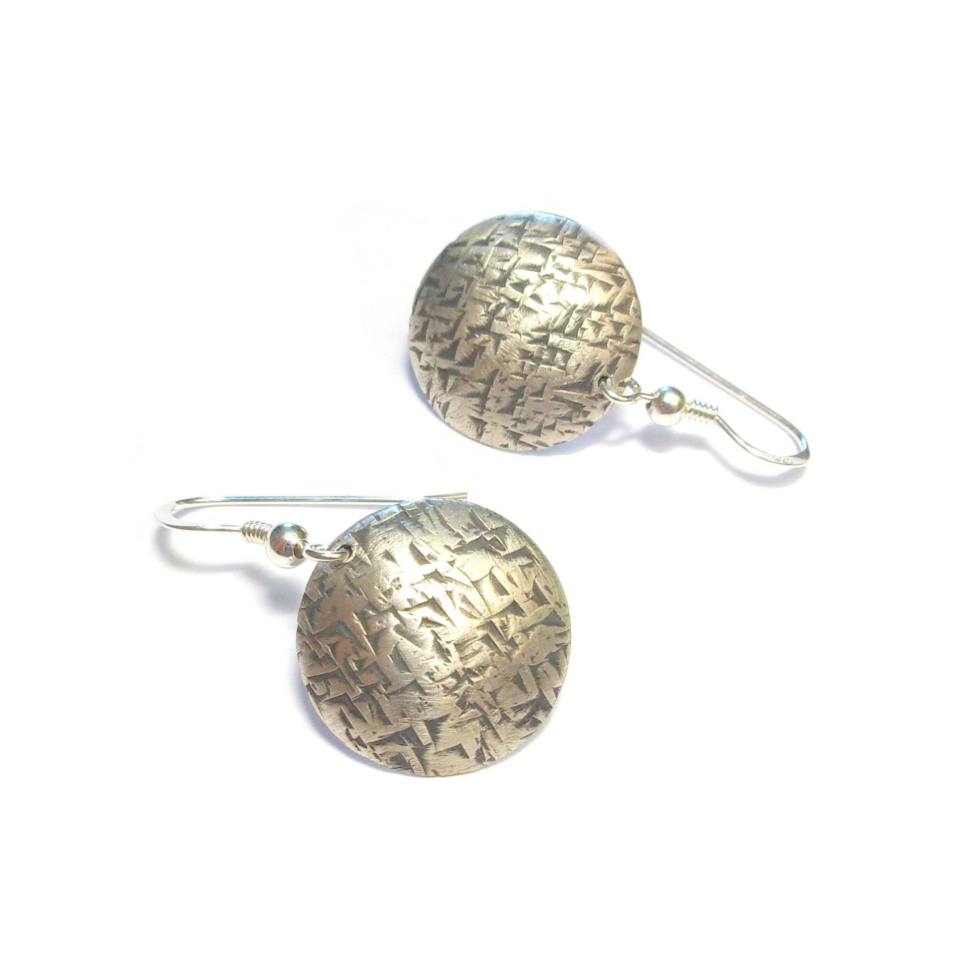 Boucles d'oreilles ethniques rondes en argent massif martelé et patiné. Assorties à la manchette Aimorés, elles composent un ensemble bohème chic qui séduit par son élégance.