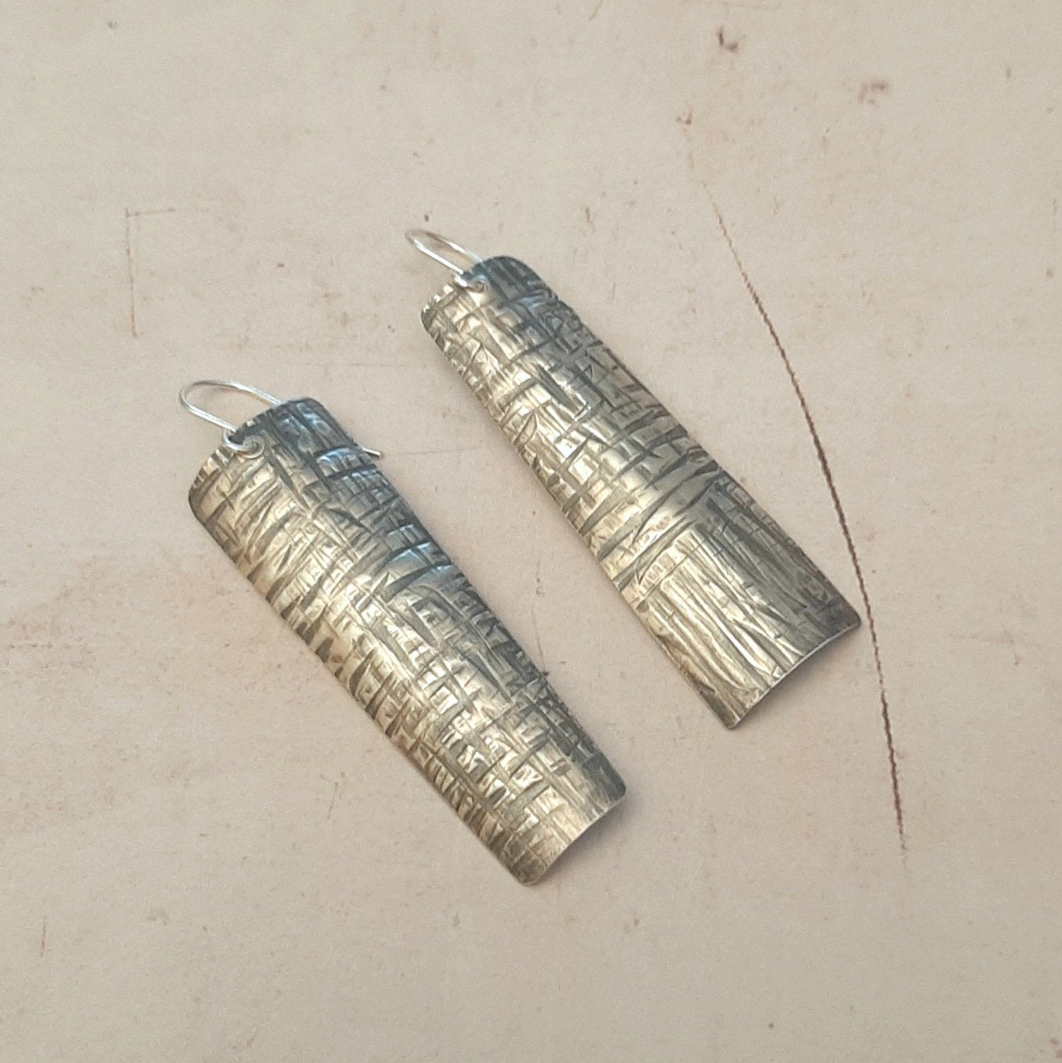 Boucles d'oreilles longues ethniques en argent massif martelé, légèrement asymétriques. Les reliefs, révélés par la patine, évoquent le tronc du "tucum", palmier tropical.