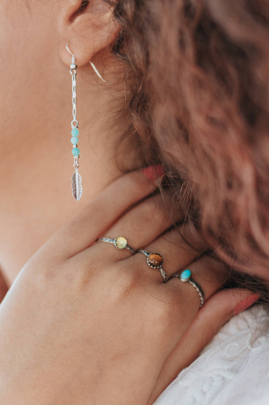Boucles d'oreilles en argent 925, ornées de pierres naturelles d'amazonite. Longueur: 6,8 cm. L’amazonite, pierre apaisante, éveille la joie de vivre et aide à vivre l’instant présent. Les plumes ajoutent une touche symbolique, représentant la présence d'un Ange ou d'un Guide, et symbolisent la paix et la liberté d'esprit selon les Amérindiens.