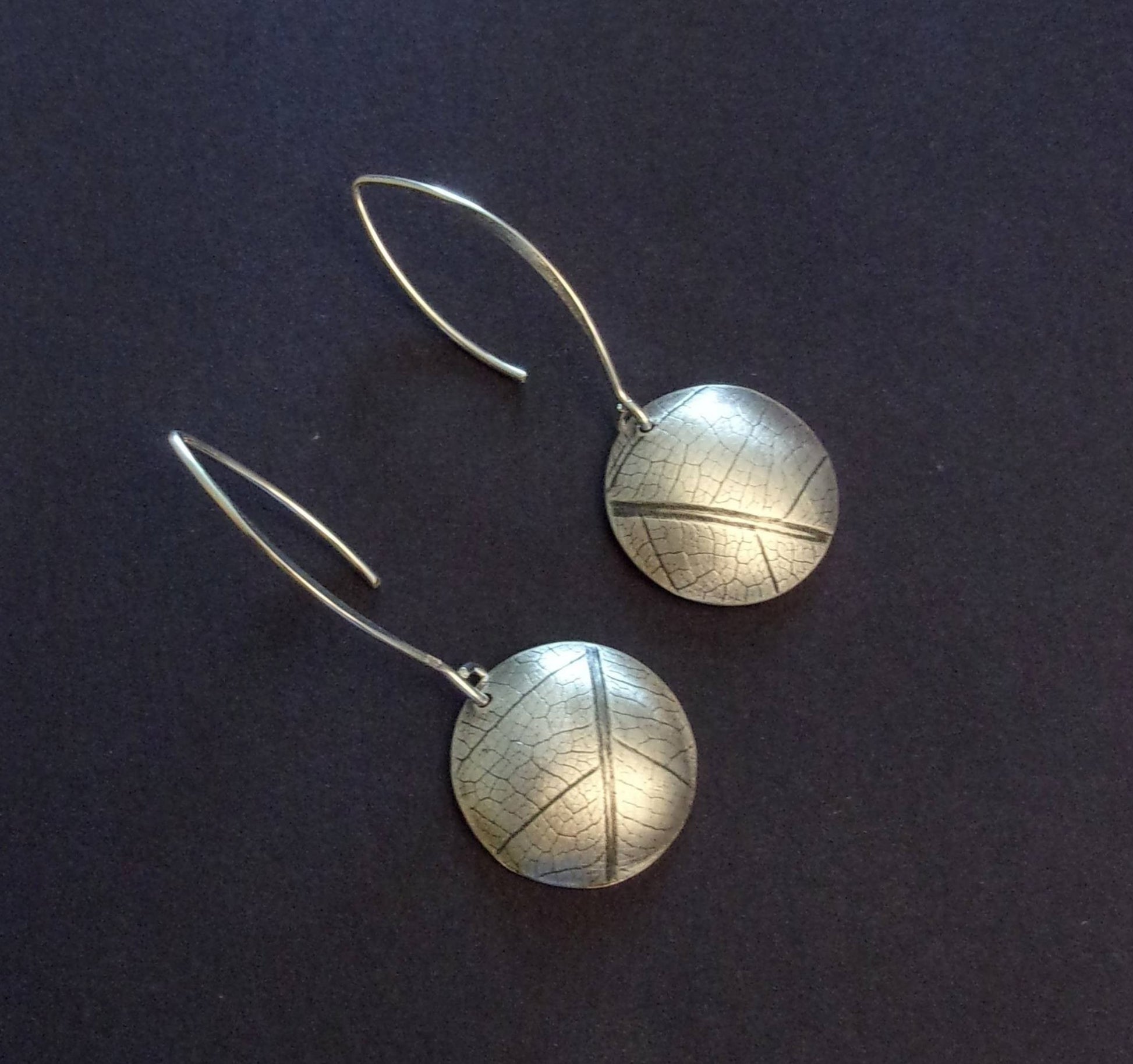 Boucles d'oreilles ethniques en argent massif gravé et patiné, avec une délicate empreinte de feuille de fruit de la passion. Chaque bijou présente une touche d'élégance naturelle et originale. La longueur est d'environ 4.6 cm et le diamètre du disque est d'environ 18 mm.