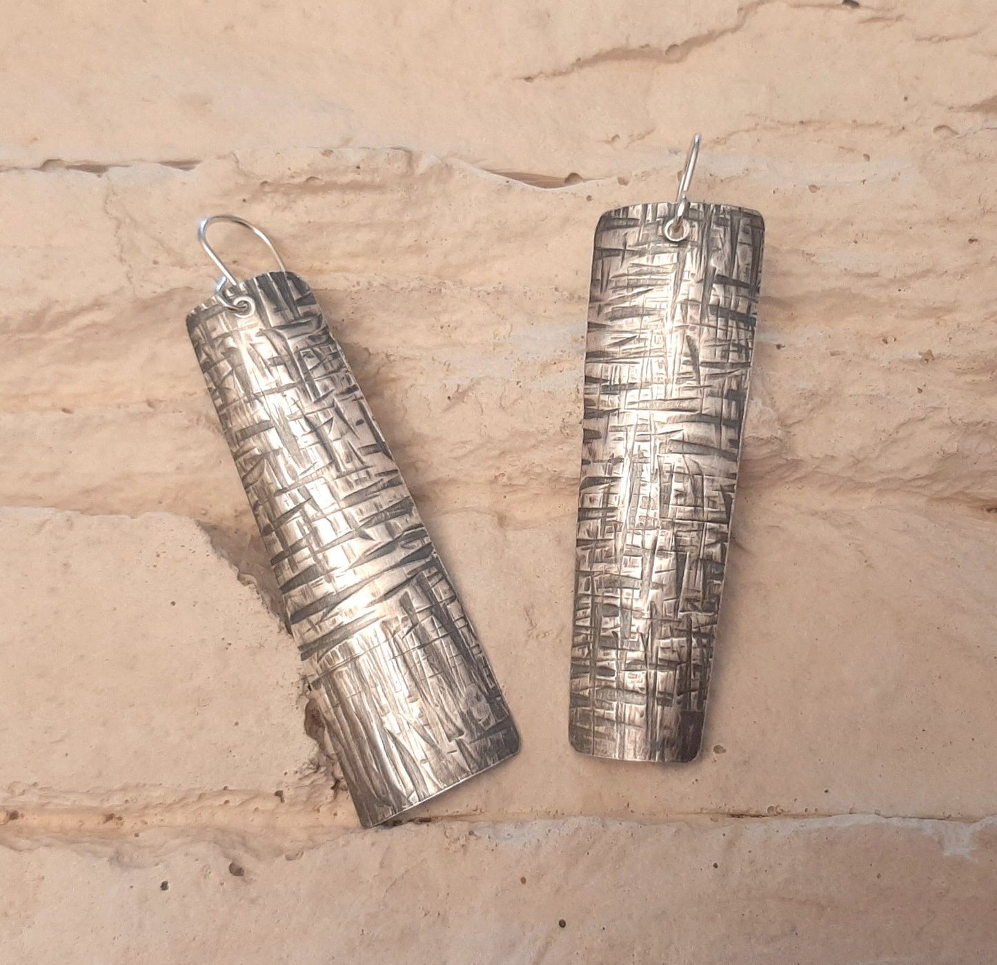 Boucles d'oreilles ethniques en argent massif martelé, légèrement asymétriques. Les reliefs, révélés par la patine, évoquent le tronc du "tucum", palmier tropical.
