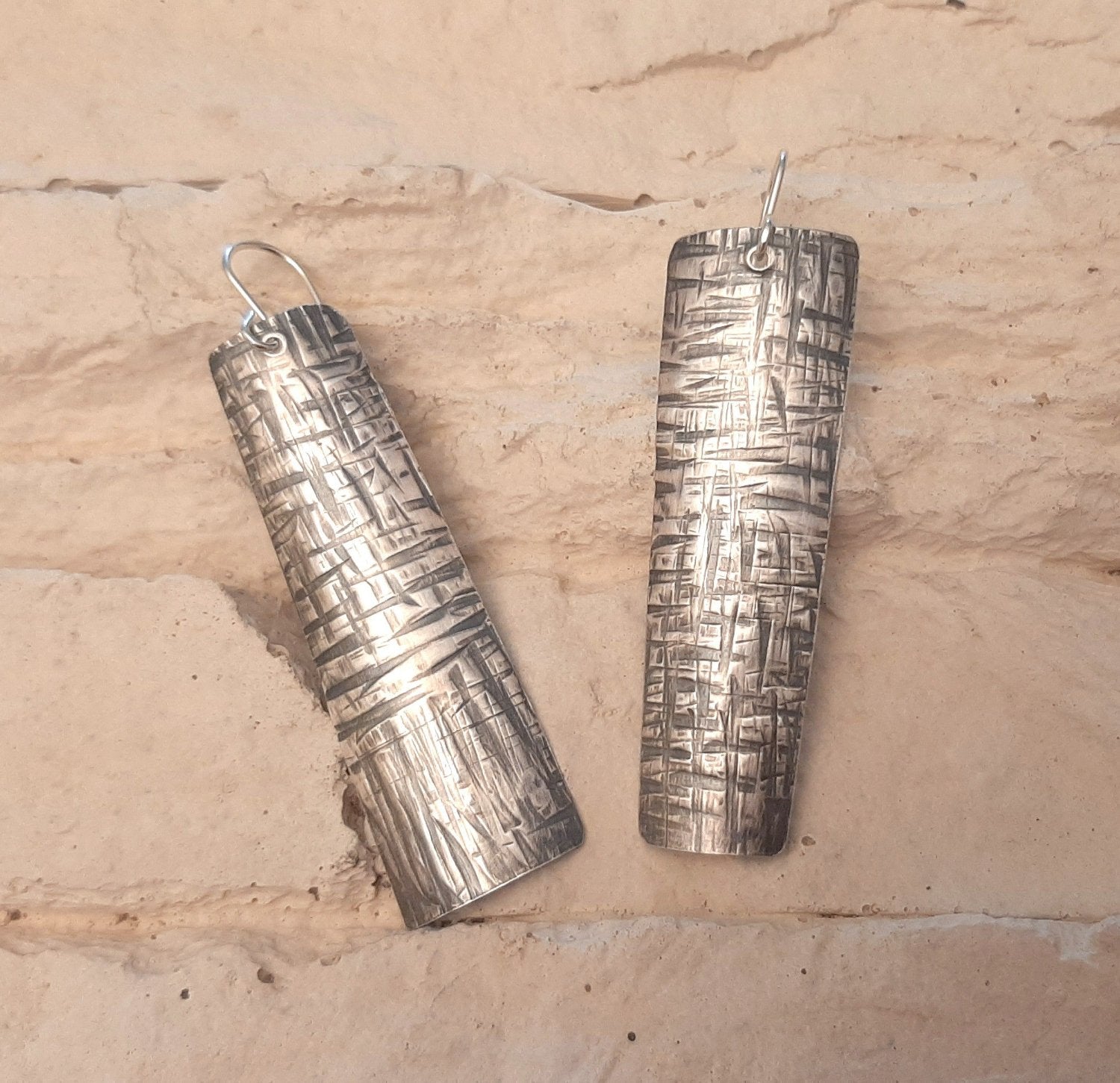 Boucles d'oreilles ethniques en argent massif martelé, légèrement asymétriques. Les reliefs, révélés par la patine, évoquent le tronc du "tucum", palmier tropical.