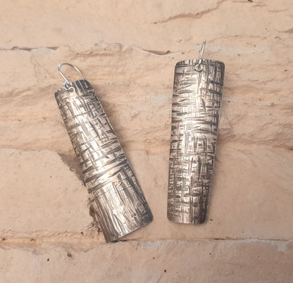 Boucles d'oreilles ethniques en argent massif martelé, légèrement asymétriques. Les reliefs, révélés par la patine, évoquent le tronc du "tucum", palmier tropical.