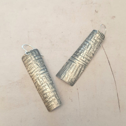 Boucles d'oreilles ethniques en argent massif martelé, légèrement asymétriques. Les reliefs, révélés par la patine, évoquent le tronc du "tucum", palmier tropical.