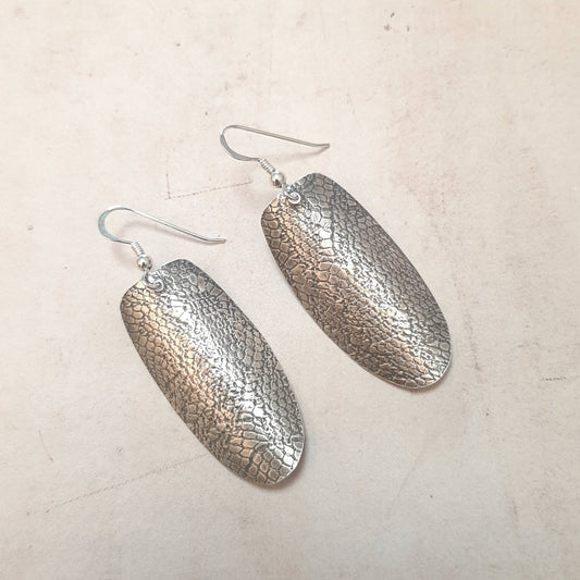 Boucles d'oreilles ethniques en argent massif patiné et texturé avec une empreinte de dentelle ancienne. Chaque bijou est façonné à la main, rendant chaque pièce unique avec de petites variations possibles par rapport au modèle photographié. La longueur est d'environ 5.6 cm.