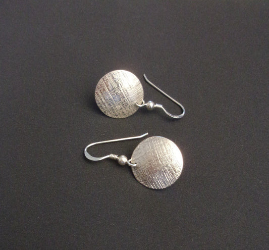 Boucles d'oreilles rondes en argent massif, avec un design délicatement ciselé apportant une touche d'élégance subtile. Leur légèreté et discrétion les rendent idéales pour une utilisation quotidienne, ajoutant une note de style raffinée à toutes les tenues.