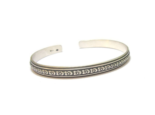 Sublimez votre poignet avec le bracelet Angra, un jonc rigide en argent massif 925, fabriqué à la main. Son design ethnique raffiné et sa taille ajustable en font un bijou unique, idéal pour un style bohème chic au quotidien.