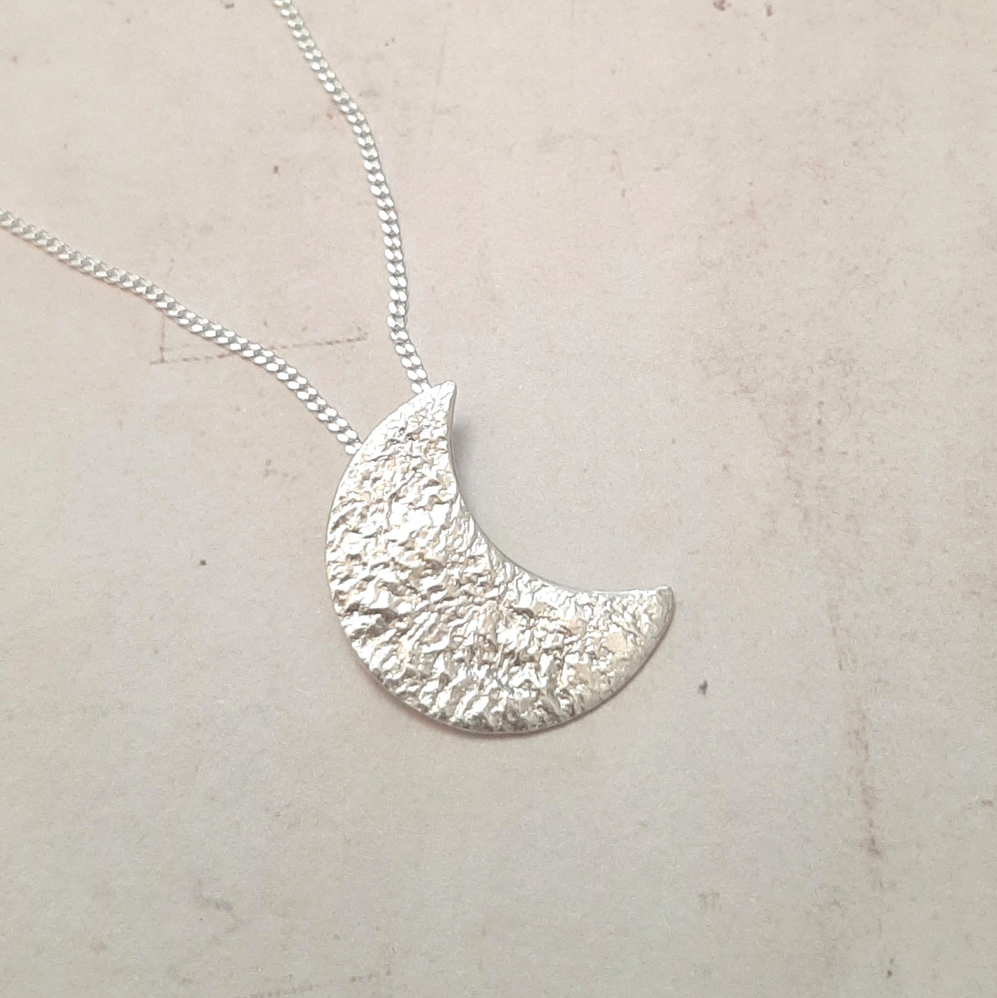 Collier avec un pendentif croissant de lune en argent massif réticulé.