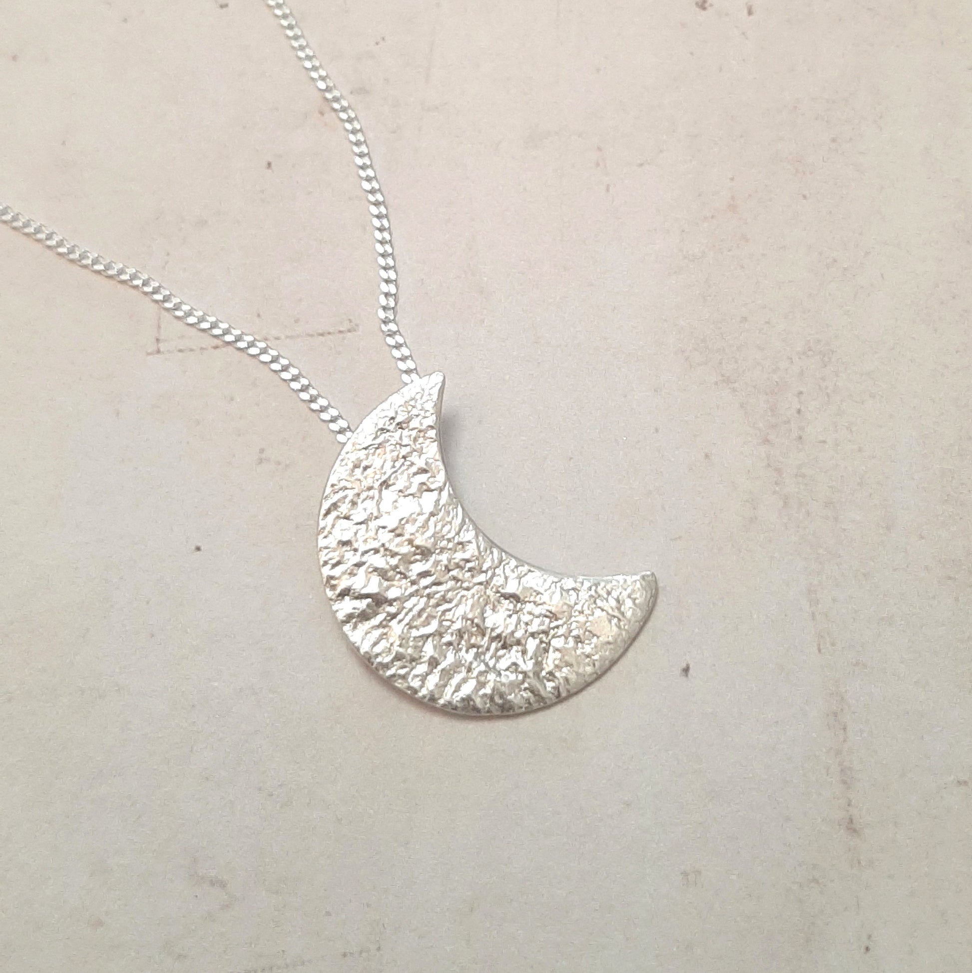 Collier avec un pendentif croissant de lune en argent massif réticulé.
