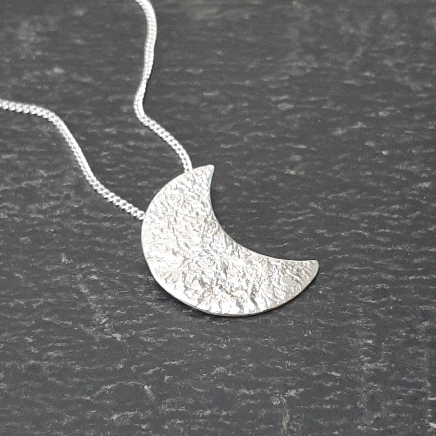 Collier avec un pendentif fait main en forme de croissant de lune en argent massif réticulé.