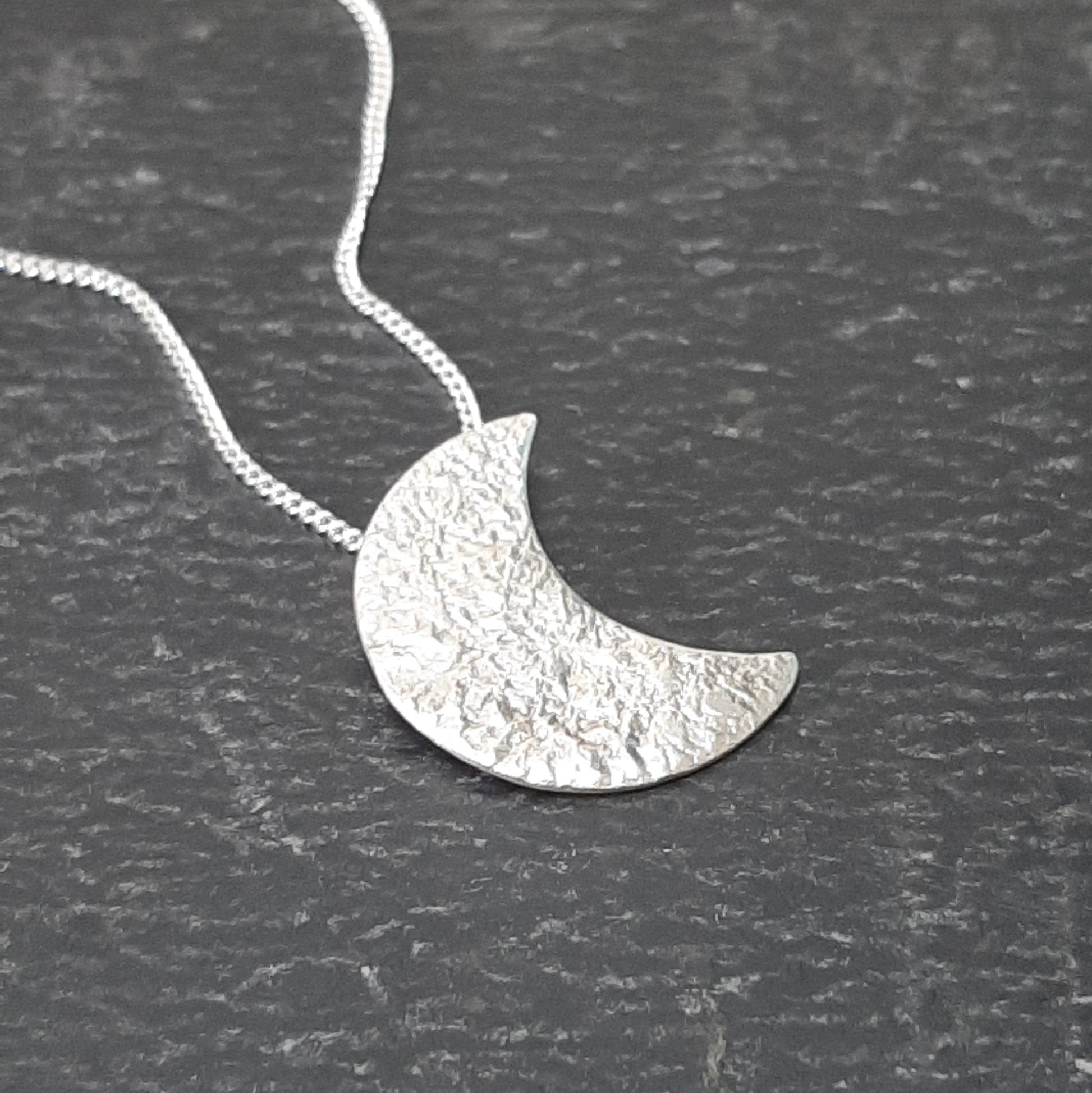 Collier avec un pendentif fait main en forme de croissant de lune en argent massif réticulé.