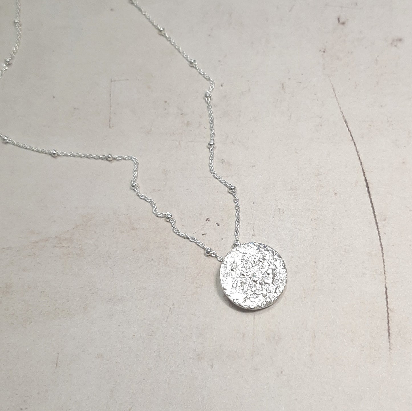 Le collier Jaci est inspiré par la pleine lune, symbole de féminité, d'intuition et de renouveau. La lune a été un guide spirituel pour de nombreuses civilisations, et ce bijou capture cette essence mystique. Réalisé en argent massif, il allie élégance et simplicité, faisant de ce collier un talisman unique. Idéal pour les amoureux de la nature et ceux cherchant des bijoux au sens profond, le collier Jaci est un choix éthique et artisanal.