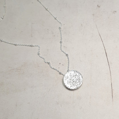 Le collier Jaci est inspiré par la pleine lune, symbole de féminité, d'intuition et de renouveau. La lune a été un guide spirituel pour de nombreuses civilisations, et ce bijou capture cette essence mystique. Réalisé en argent massif, il allie élégance et simplicité, faisant de ce collier un talisman unique. Idéal pour les amoureux de la nature et ceux cherchant des bijoux au sens profond, le collier Jaci est un choix éthique et artisanal.