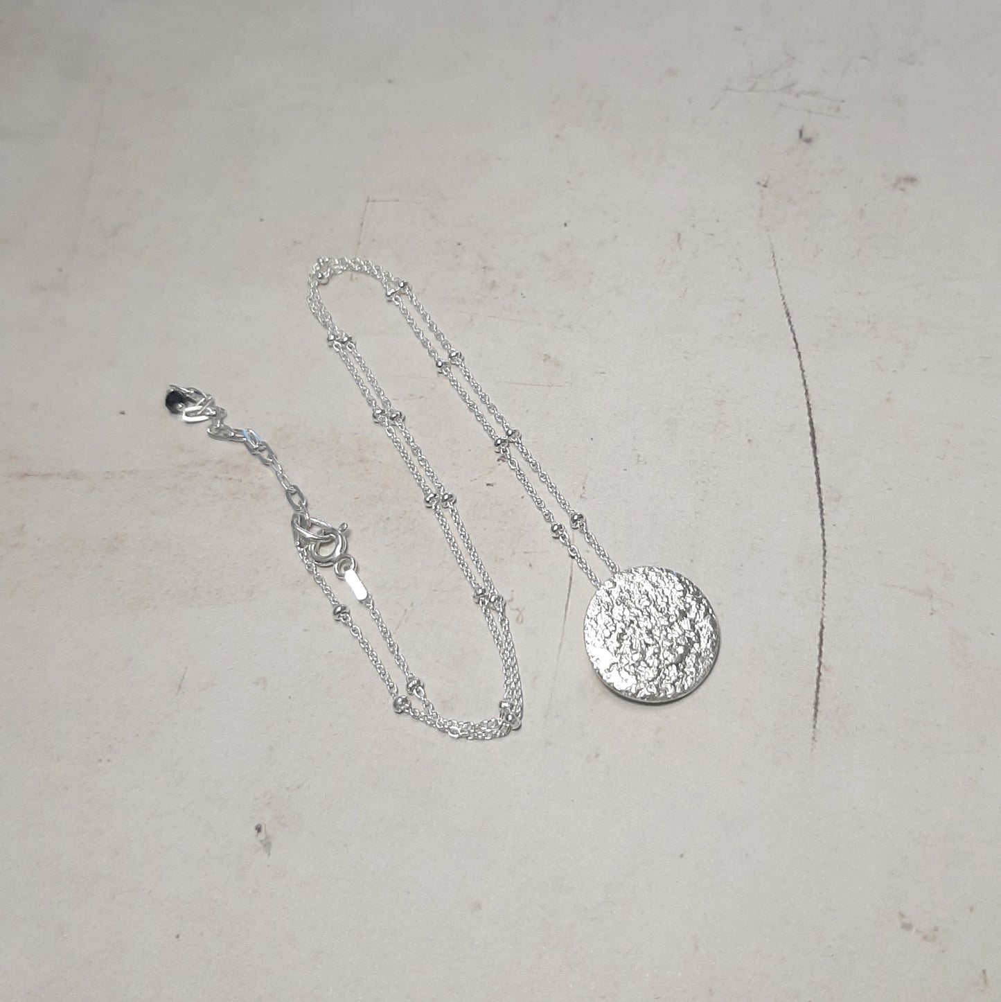 Collier artisanal avec un pendentif en forme de pleine lune en argent massif réticulé. 