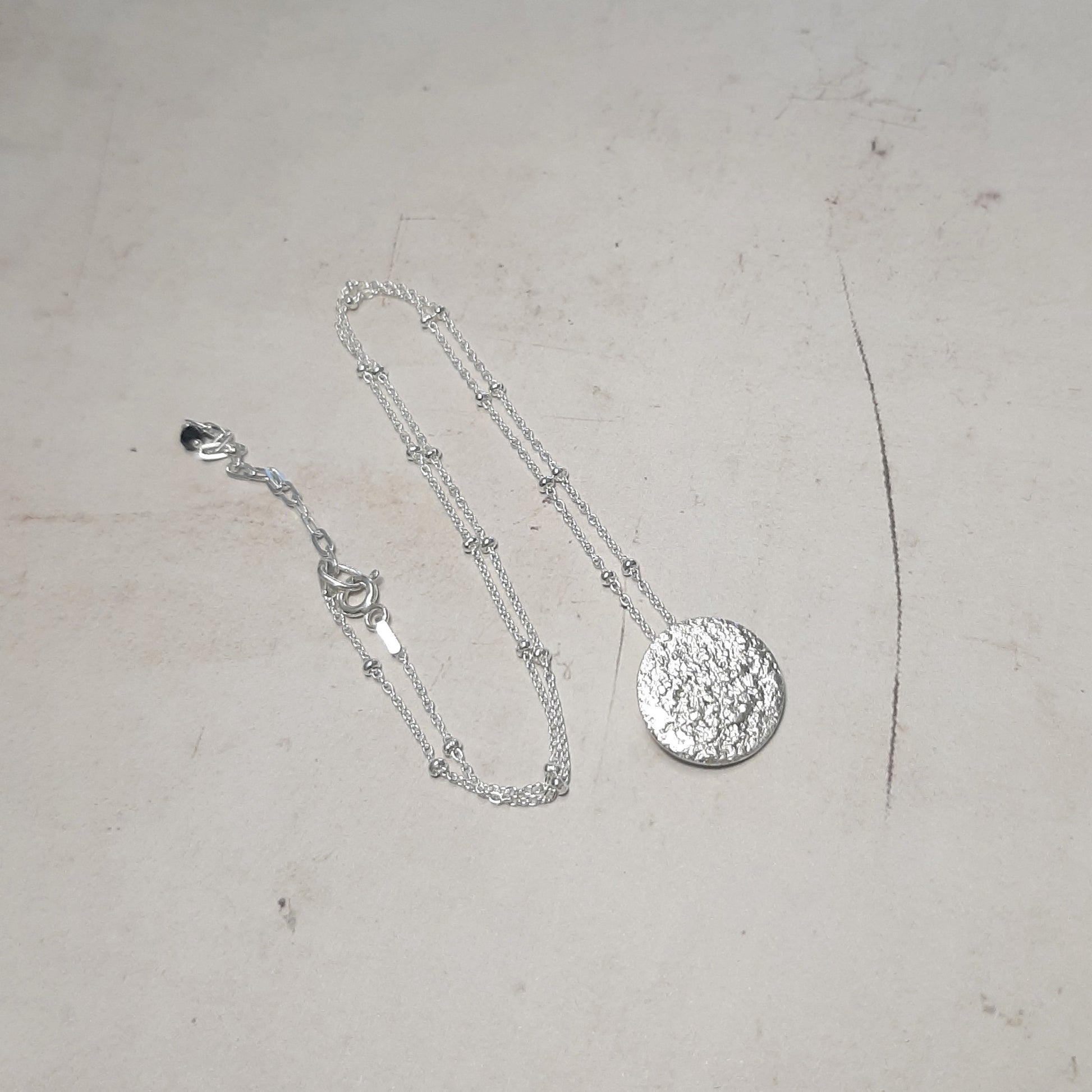 Collier artisanal avec un pendentif en forme de pleine lune en argent massif réticulé. 