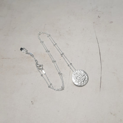 Collier artisanal avec un pendentif en forme de pleine lune en argent massif réticulé. 