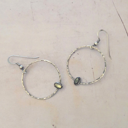 Boucles d'oreilles ethniques en argent massif patiné, rehaussées de nacre naturelle. Chaque bijou unique révèle des reflets éclatants.
