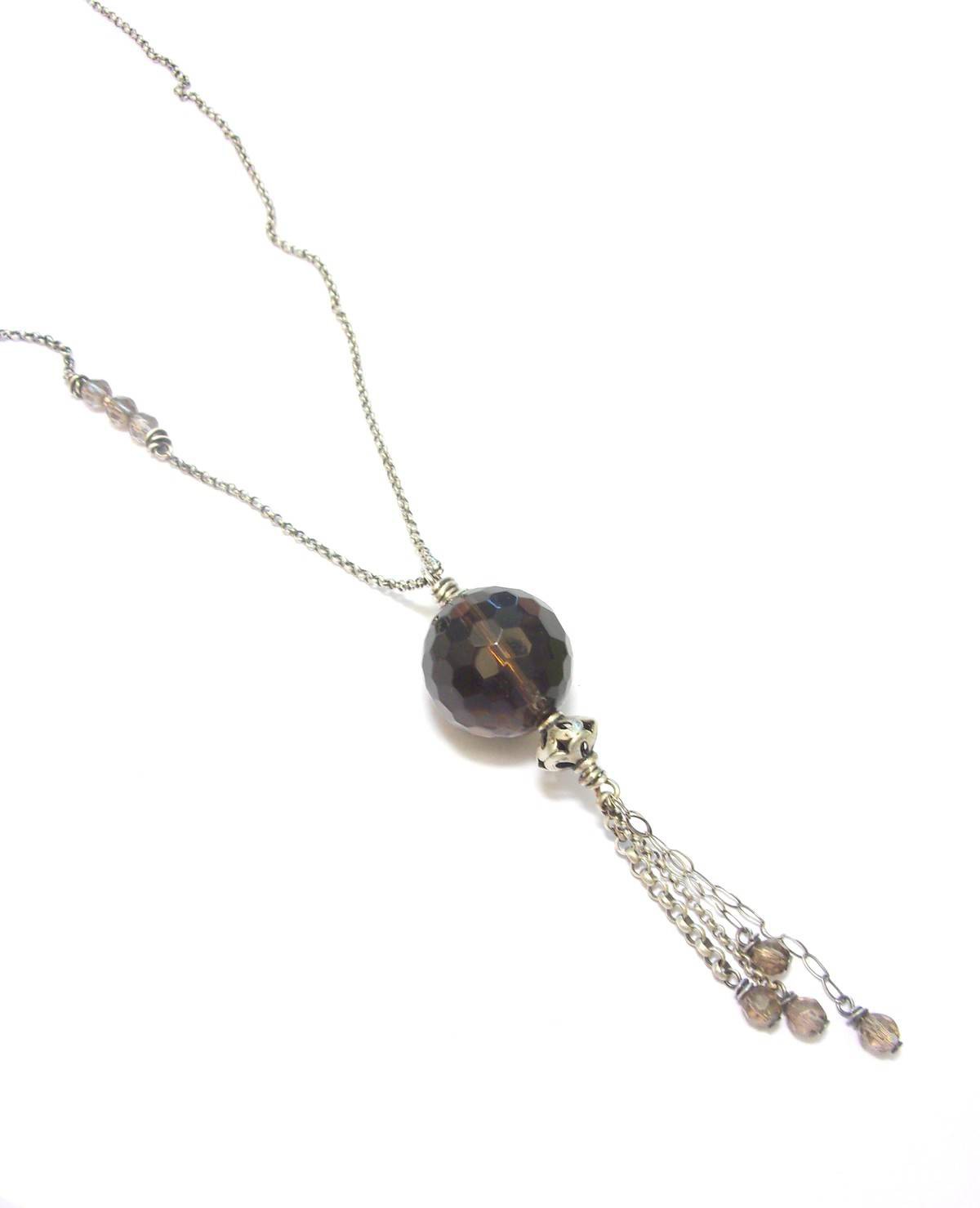 Sautoir ethnique en argent 925 patiné, orné d'un pendentif en quartz fumé, une pierre semi-précieuse aux vertus apaisantes. Ce collier long de 90 cm sans fermoir met en valeur un quartz de 18 mm, apportant à la fois élégance et bien-être. En lithothérapie, le quartz fumé aide à surmonter le stress et les moments difficiles, favorisant le calme émotionnel et la réduction des peurs.
