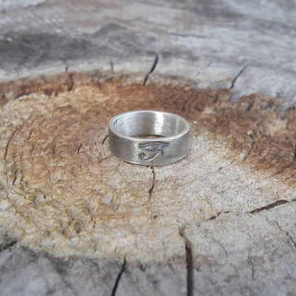 La bague fait main "Œil d'Horus" en argent massif patiné, avec une largeur d'environ 6 mm, se distingue par son design symbolique et intemporel. Unisexe, elle convient aussi bien aux hommes qu'aux femmes. L’Œil d’Horus, également appelé oudjat, est un symbole ancien de protection et de clairvoyance, souvent porté comme un porte-bonheur. 
