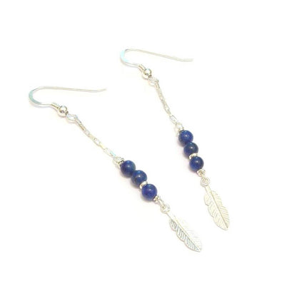 Boucles d'oreilles en argent 925 ornées de pierres naturelles de lapis-lazuli. Leur design bohème est rehaussé d'une délicate plume, symbole de légèreté et de liberté. Longueur : 6,8 cm.